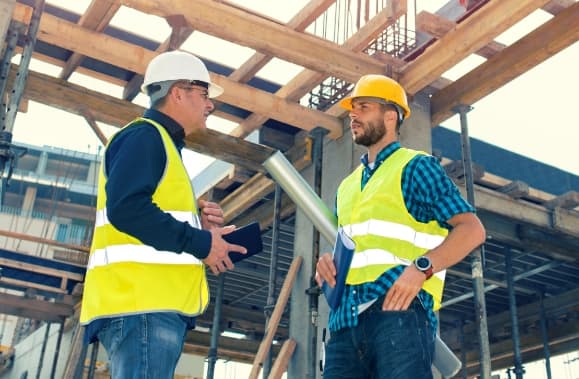 Two construction workers talking in a construction site.